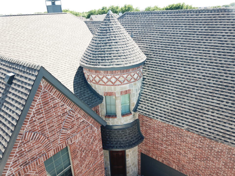 Stunning turret roof installation with decorative brick detail - McKinney luxury home